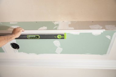 İşçi evde ruh seviyesiyle tavanı kontrol ediyor.