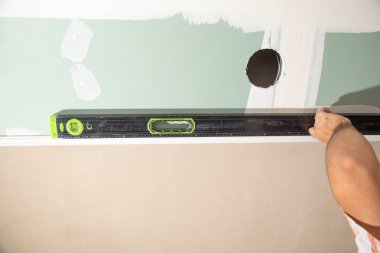 İşçi evde ruh seviyesiyle tavanı kontrol ediyor.