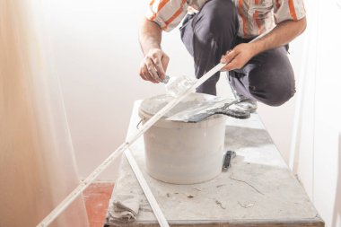 İşçi malzemeye macun sürüyor. Ev yenileniyor