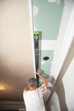 İşçi evde ruh seviyesiyle tavanı kontrol ediyor.