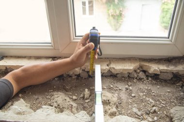 Evdeki yenilemeden önce eski pencere pervazını ölçen işçiler.