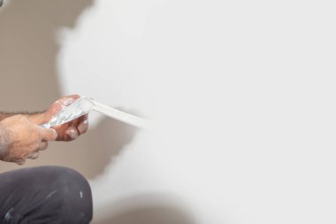 İşçi malzemeye macun sürüyor. Ev yenileniyor