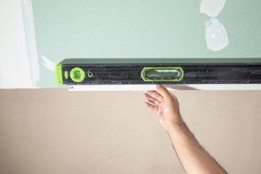 İşçi evde ruh seviyesiyle tavanı kontrol ediyor.