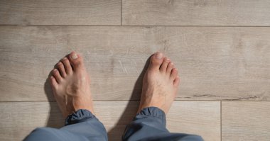 Kaplamalı zeminde yalınayak bir erkek..