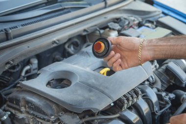 Araç motorunda yağ seviyesini kontrol eden adam.