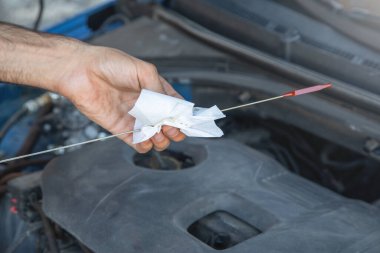Araç motorunda yağ seviyesini kontrol eden adam.