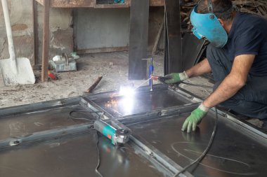 Yeni bir metal kapıyı tamir eden bir kaynakçı..