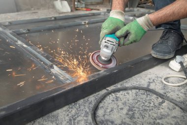  Açı öğütücü kullanan bir işçi. Demir kapının detayları kesiliyor.