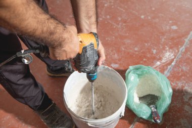 İşçi, alçı taşını kovada karıştırır..