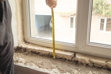 Evdeki yenilemeden önce eski pencere pervazını ölçen işçiler.