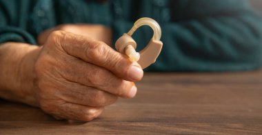 Kafkasyalı yaşlı kadın işitme cihazı tutuyor.