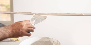 İşçi malzemeye macun sürüyor. Ev yenileniyor