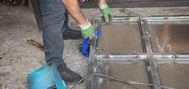 Beyaz adam yeni bir demir kapı üzerinde çalışıyor..