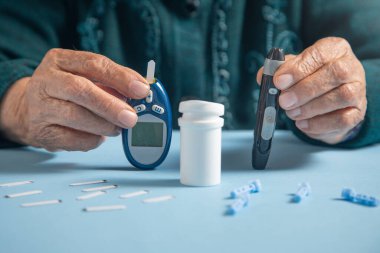 Kan şekeri ölçer ve mızraklı yaşlı kadın elleri..