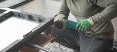  Açı öğütücü kullanan bir işçi. Demir kapının detayları kesiliyor.