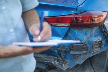 Arabasının yanında not defteri olan bir sigortacı..