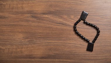 Rosary beads on the wooden background.