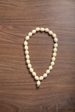 Rosary beads on the wooden background.