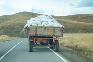 Yol boyunca meyve çuvalları taşıyan traktör..