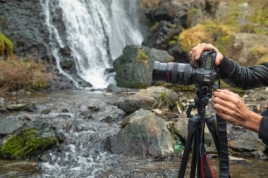 Elinde dijital bir fotoğraf makinesi olan fotoğrafçı doğada fotoğraf çekiyor..