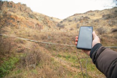 Erkek eli, akıllı telefonu doğada gösteriyor. Sinyal yok.