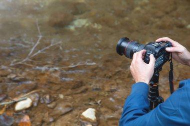 Elinde dijital bir fotoğraf makinesi olan fotoğrafçı doğada fotoğraf çekiyor..