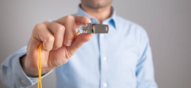 Metal düdük tutan hakem ya da antrenör.