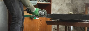  Açı öğütücü kullanan bir işçi. Demir kapının detayları kesiliyor.