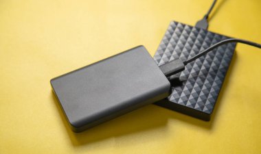 Sarı arkaplanda kablo olan harici sabit disk.