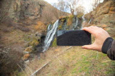 Erkek eli, akıllı telefonu doğada gösteriyor. Sinyal yok.