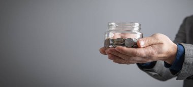 Bozuk para kavanozu gösteren bir adam. İş dünyası