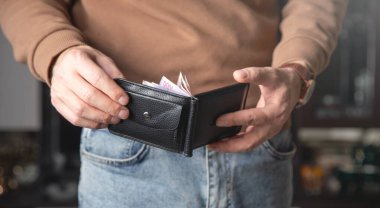 Kafkasyalı genç adam evde cüzdanını gösteriyor..