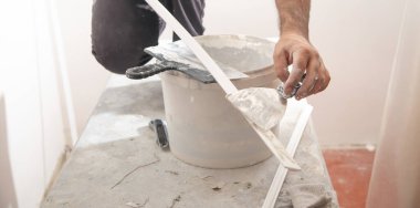 İşçi malzemeye macun sürüyor. Ev yenileniyor