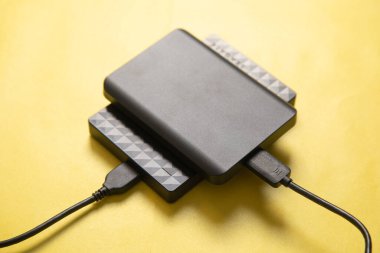 Sarı arkaplanda kablo olan harici sabit disk.