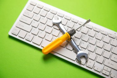 Bilgisayar klavyeli İngiliz anahtarı ve tornavida. Bilgi İşlem. Destekle