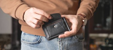 Kafkasyalı genç adam evde cüzdanını gösteriyor..