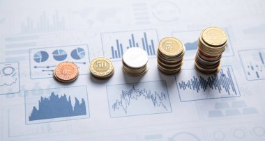 Finansal büyüme grafiklerine sahip bozuk para yığını.