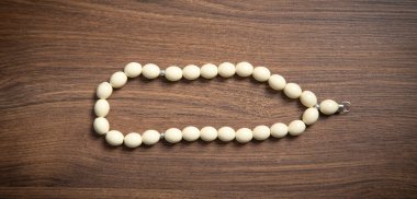 Rosary beads on the wooden background.