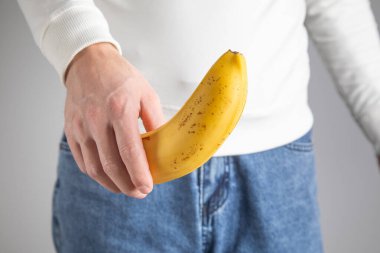 Pantolonunun üstünde muz gösteren bir adam..