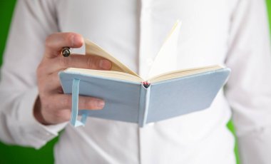 Elinde kalemle not defteri tutan adam..