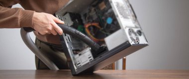 Adam bilgisayar kılıfını elektrikli süpürgeyle temizliyor..