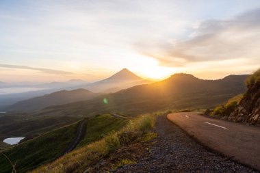 Güneşin doğuşunda, etrafı sisli dağ katmanlarıyla çevrili görkemli bir volkan nefes kesici bir manzara yaratıyor..