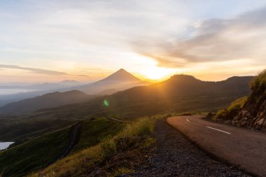 Güneşin doğuşunda, etrafı sisli dağ katmanlarıyla çevrili görkemli bir volkan nefes kesici bir manzara yaratıyor..