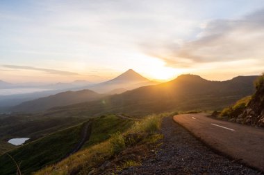 Güneşin doğuşunda, etrafı sisli dağ katmanlarıyla çevrili görkemli bir volkan nefes kesici bir manzara yaratıyor..