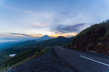 Güneşin doğuşunda, etrafı sisli dağ katmanlarıyla çevrili görkemli bir volkan nefes kesici bir manzara yaratıyor..