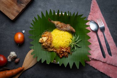 Otantik Endonezya Nasi Kuning muz yaprakları üzerinde kızarmış balık, vermicelli, tempeh, fıstık ve taze otlarla servis edildi. Endonezya 'dan canlı ve lezzetli bir geleneksel yemek..