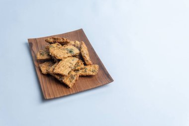 Kırsal ahşap bir tabakta düzenlenmiş geleneksel Endonezya tempeh krakerleri. Otantik mutfak temaları, sokak yemekleri konseptleri ve atıştırmalık görsel şeyler için mükemmel..