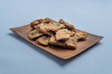 Kırsal ahşap bir tabakta düzenlenmiş geleneksel Endonezya tempeh krakerleri. Otantik mutfak temaları, sokak yemekleri konseptleri ve atıştırmalık görsel şeyler için mükemmel..