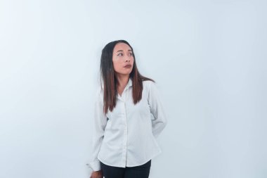 Endonezyalı kadın, yan tarafa bakarken yorgun bir ifadeyle ayakta duruyor. Temiz beyaz arkaplan, stres, tükenme, yorgunluk ya da duygusal anlar gibi konular için uygun hale getirir..