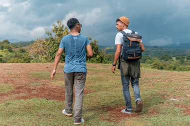 İki yürüyüşçü bir tepede yürüyor, doğa manzarasının tadını çıkarıyor, doğa manzarasını keşfediyor ve doğanın güzelliğini kucaklıyor.